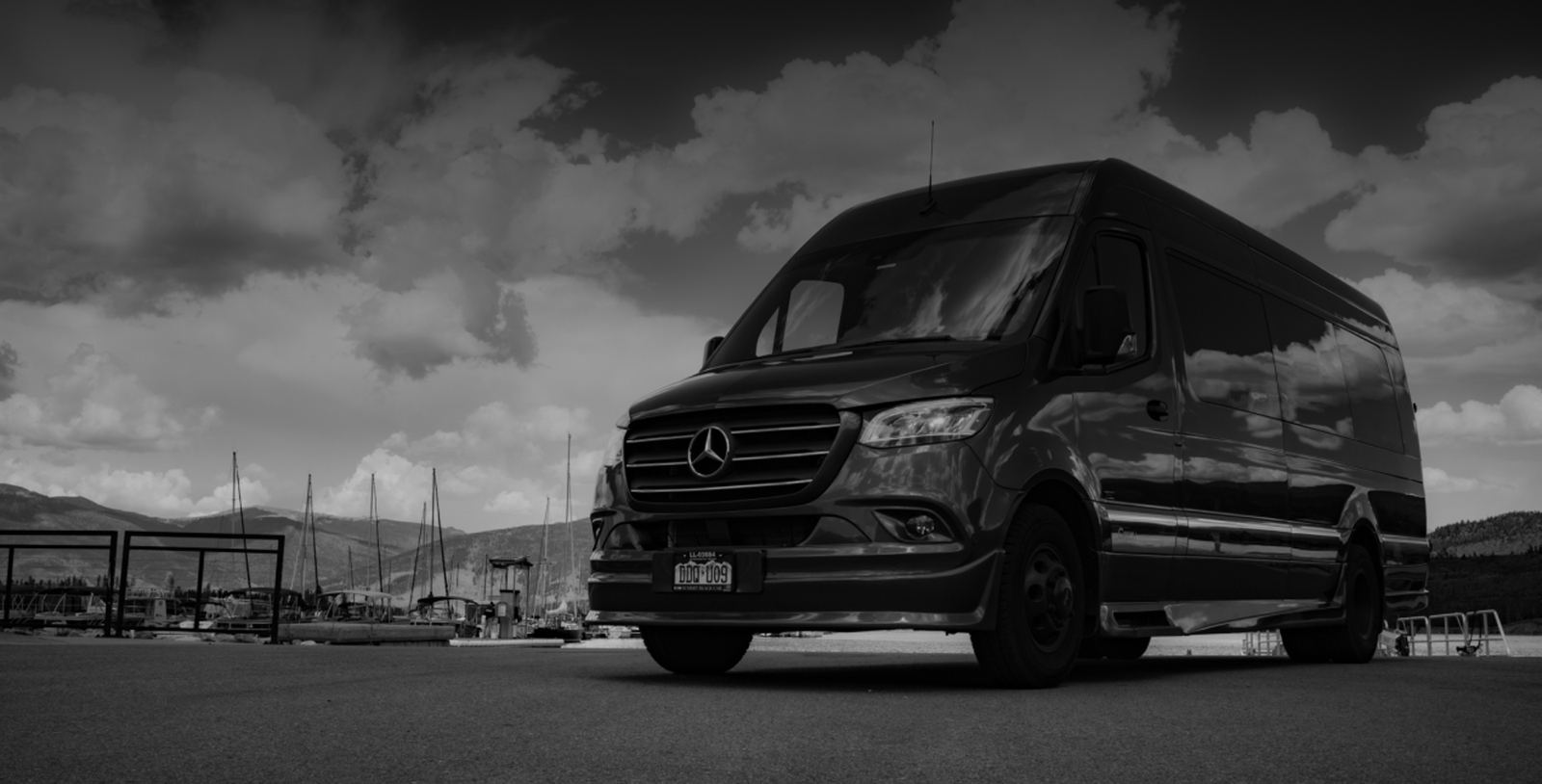 Summit Black Car Mercedes-Benz Sprinter executive van at a Summit County marina with mountains behind